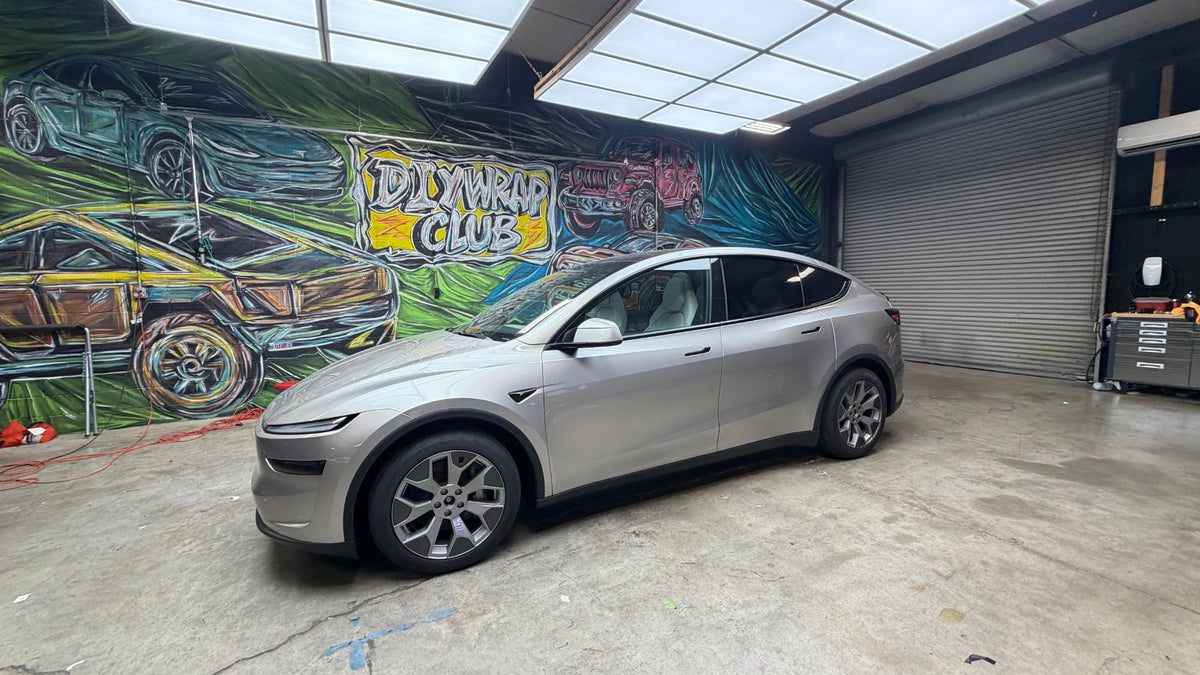 Tesla Model Y in the DIY Wrap Club shop in front of the club mural